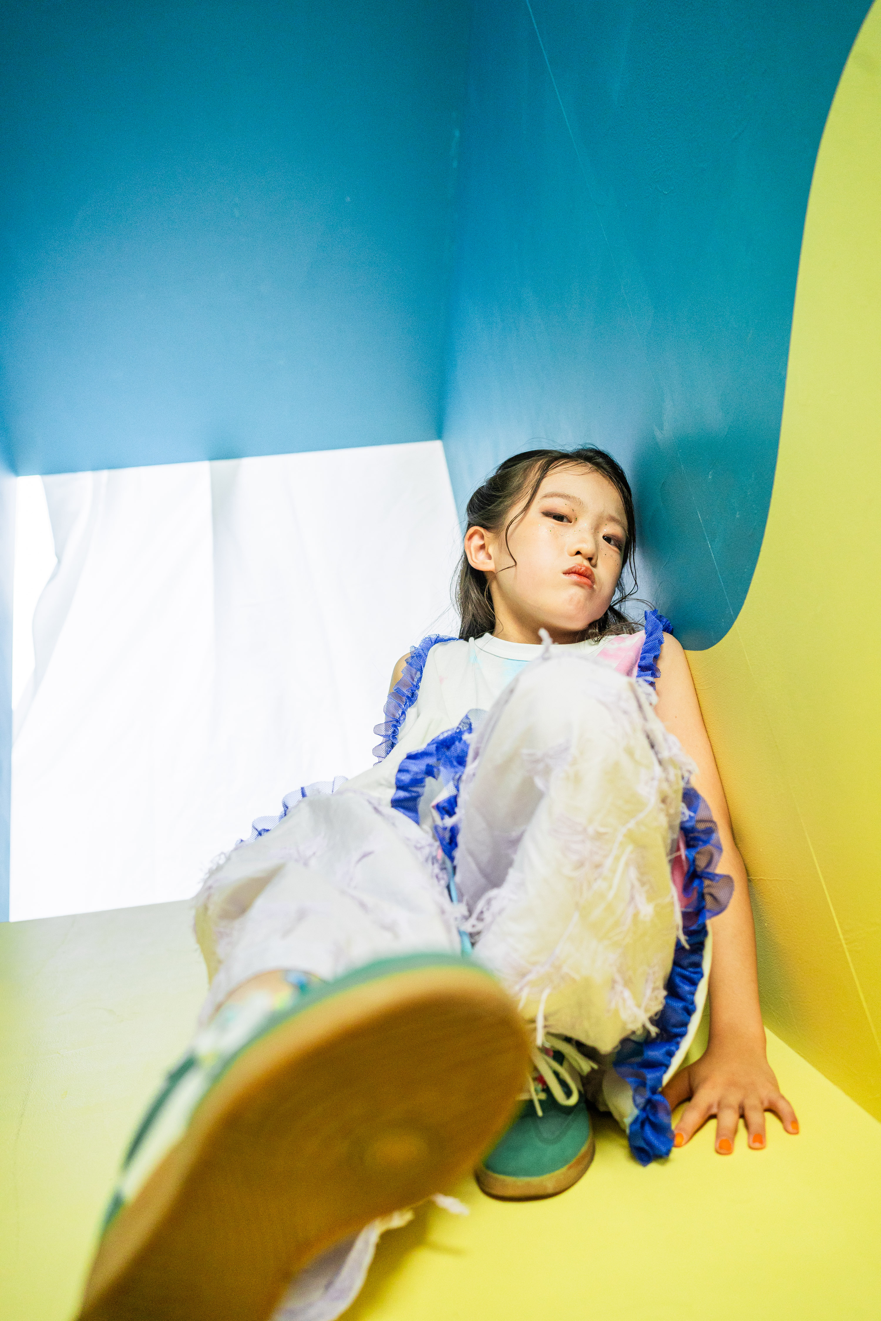 青と黄色のカラフルな背景でポーズをとるお子さんの写真
