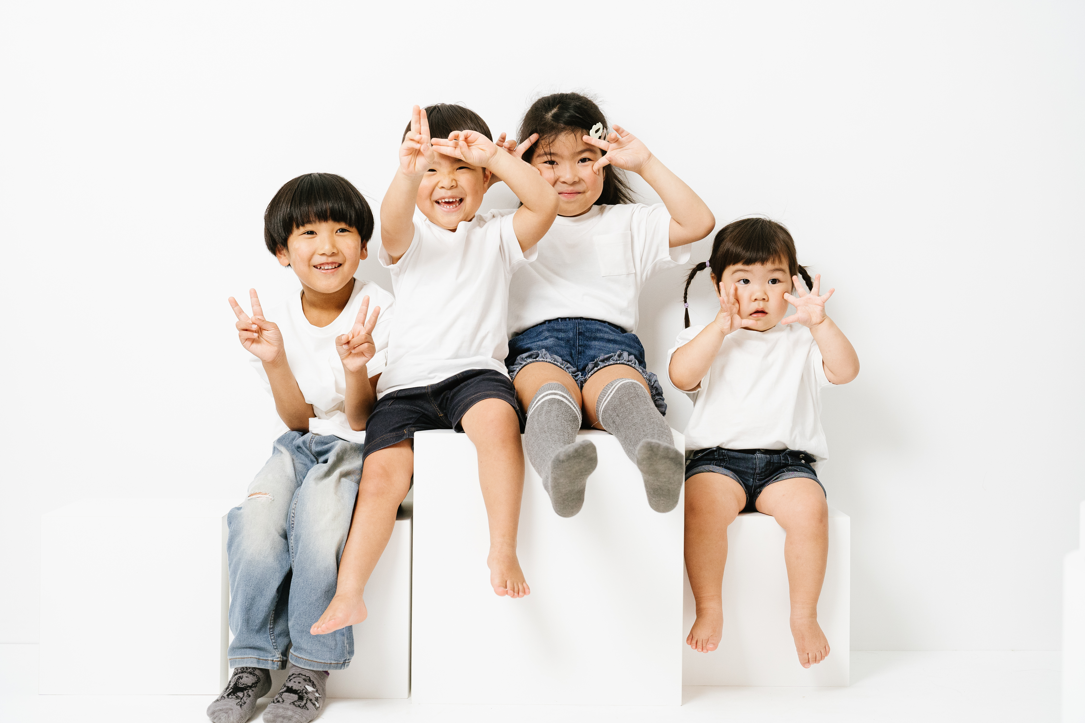 白い服を着た4人のお子さんが並んでポーズをとる写真
