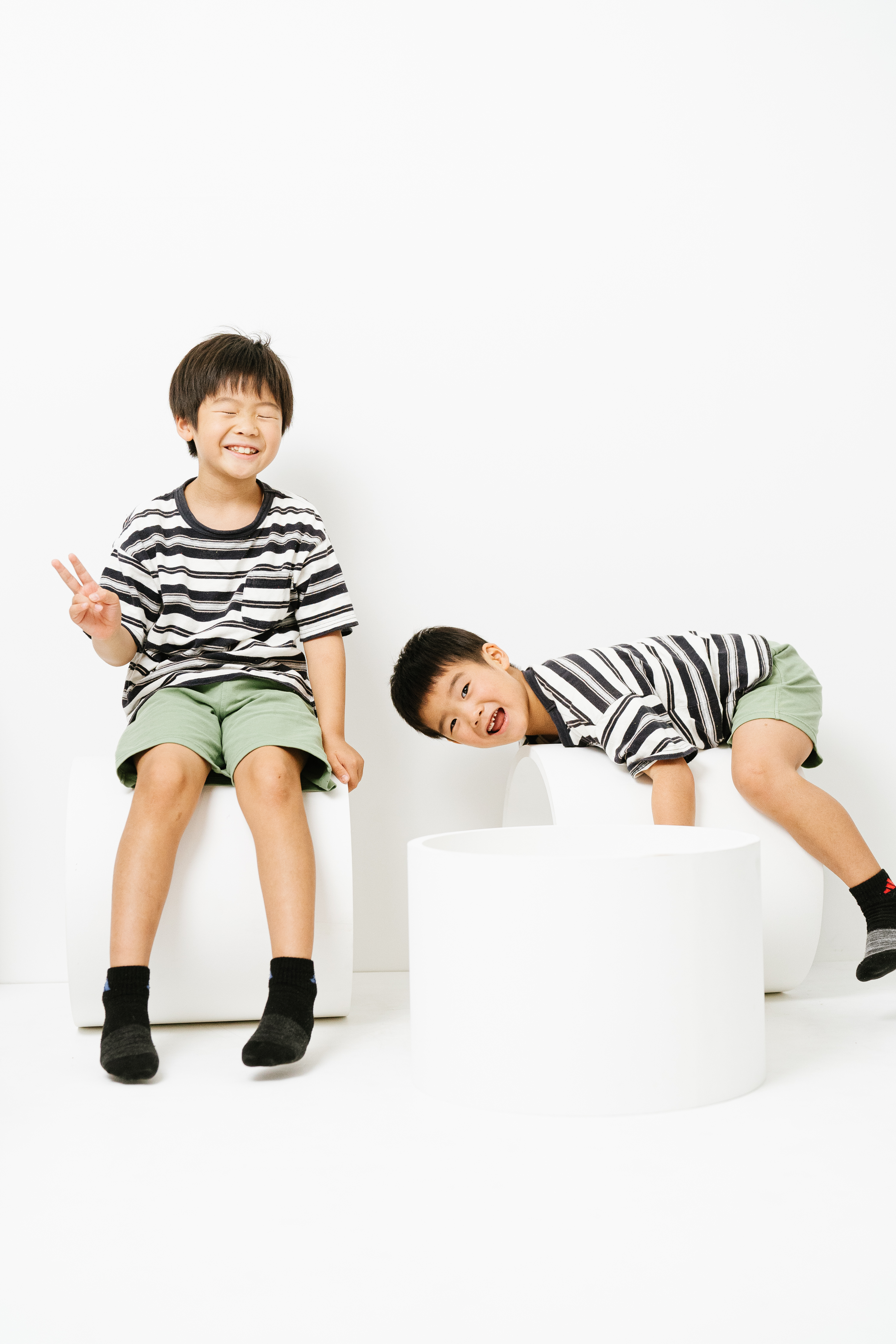おそろいの服を着たきょうだいが笑顔で遊ぶ写真